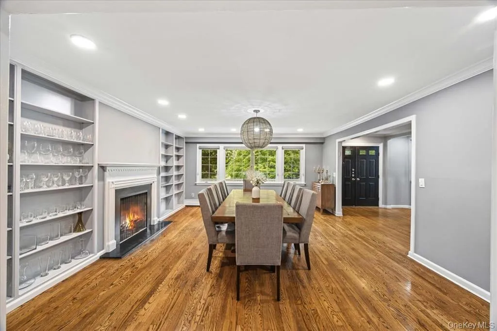 Dining area featuring wood finished floors, recessed lighting, ornamental molding, a lit fireplace, and built in features Dining area featuring wood finished floors, recessed lighting, ornamental molding, a lit fireplace, and built in features