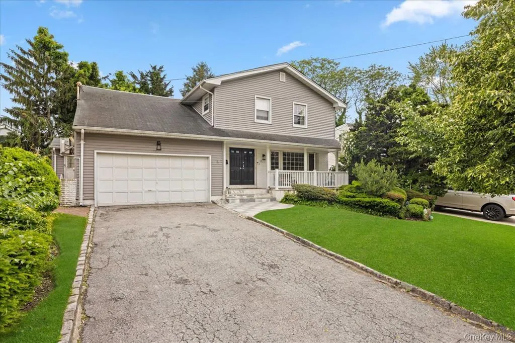 Traditional-style house featuring a front lawn, covered porch, asphalt driveway, and an attached garage Traditional-style house featuring a front lawn, covered porch, asphalt driveway, and an attached garage