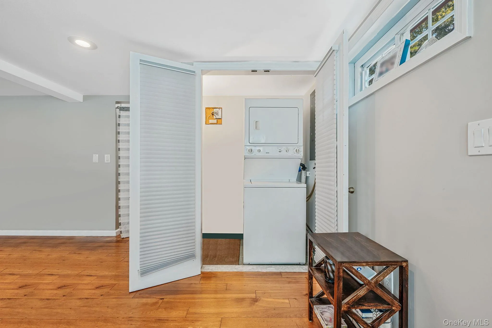 Laundry area with light wood-style flooring, stacked washer / dryer, and recessed lighting Laundry area with light wood-style flooring, stacked washer / dryer, and recessed lighting