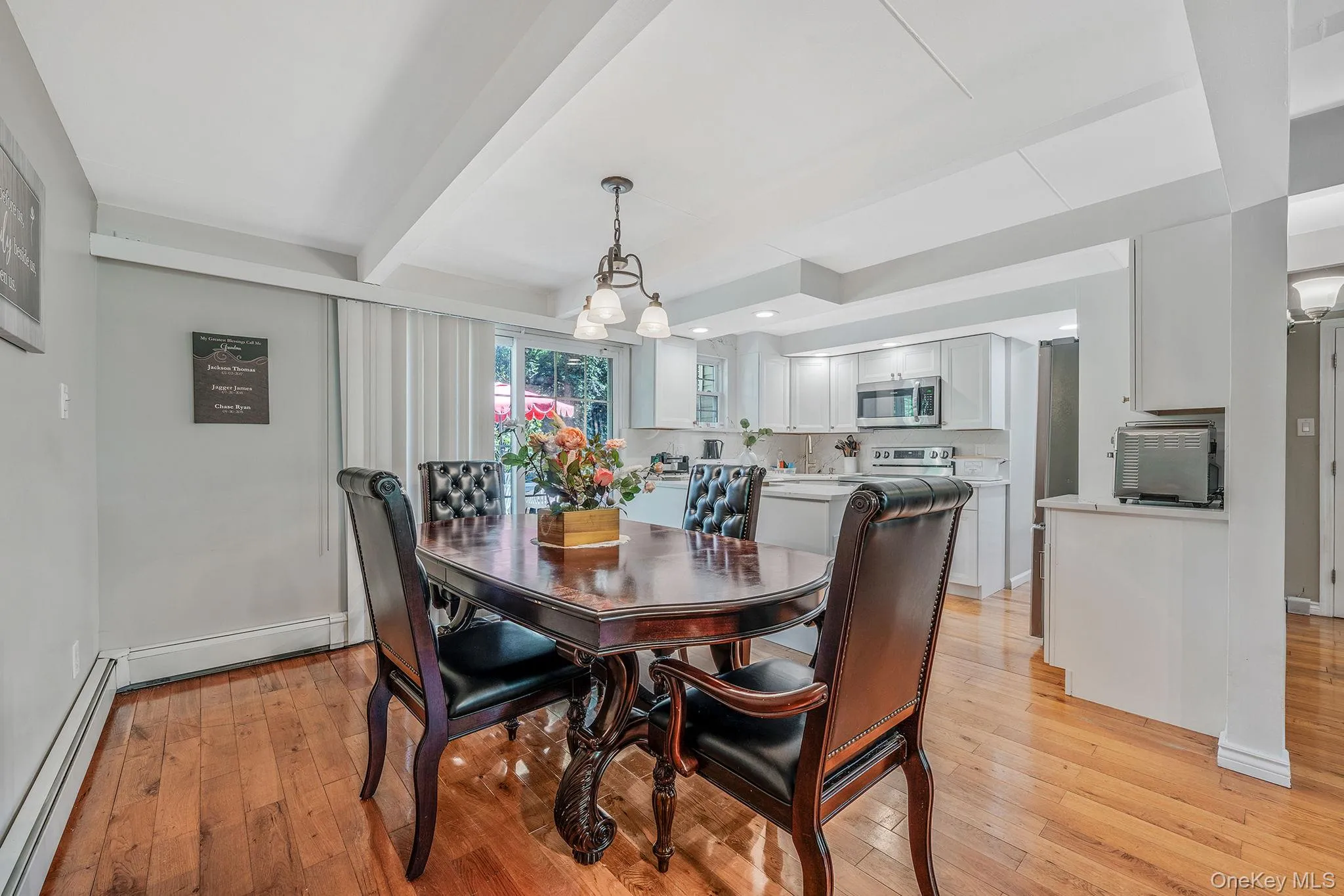 Dining room with light wood-type flooring, baseboard heating, beamed ceiling, and a baseboard heating unit Dining room with light wood-type flooring, baseboard heating, beamed ceiling, and a baseboard heating unit