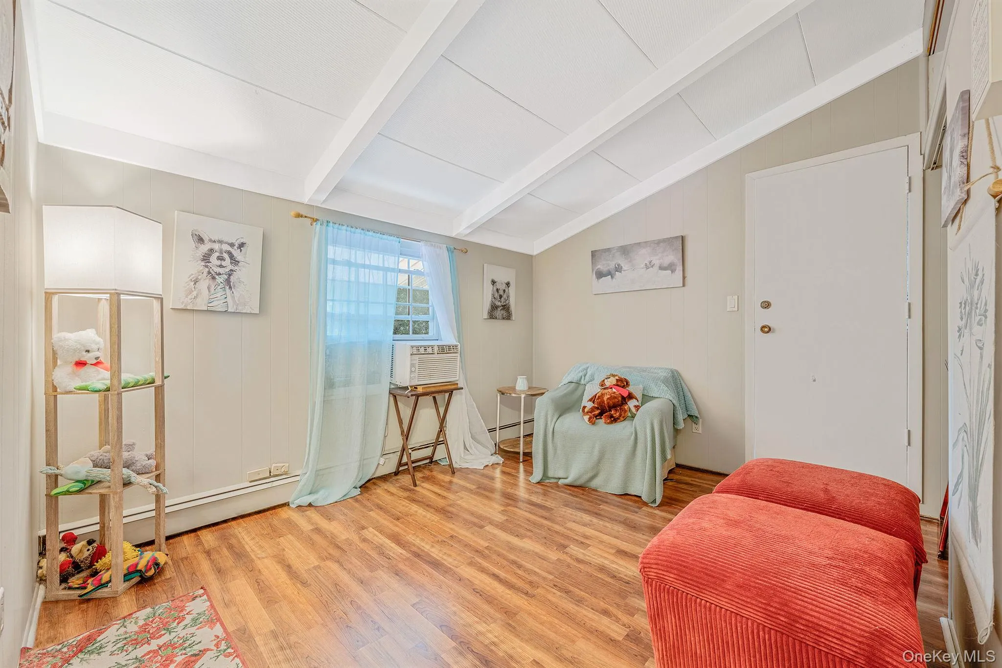 Sitting room featuring light wood-style flooring, wooden walls, baseboard heating, and cooling unit Sitting room featuring light wood-style flooring, wooden walls, baseboard heating, and cooling unit