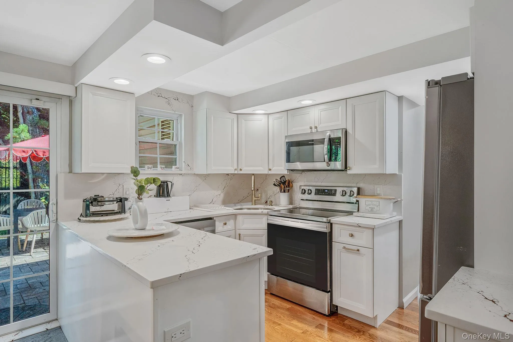 Kitchen with tasteful backsplash, appliances with stainless steel finishes, light wood-type flooring, white cabinets, and recessed lighting Kitchen with tasteful backsplash, appliances with stainless steel finishes, light wood-type flooring, white cabinets, and recessed lighting