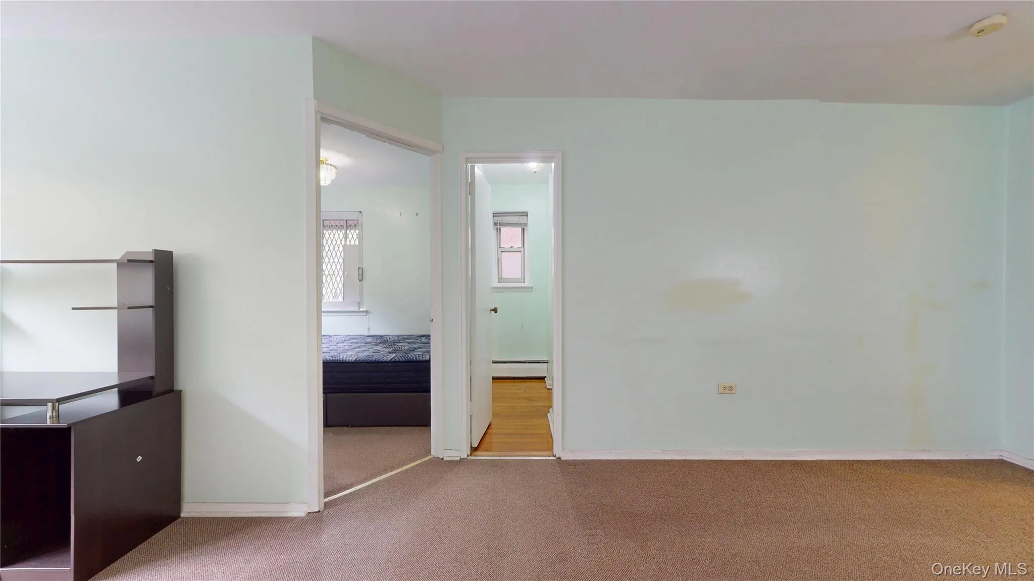 Unfurnished bedroom featuring carpet and a baseboard radiator Unfurnished bedroom featuring carpet and a baseboard radiator