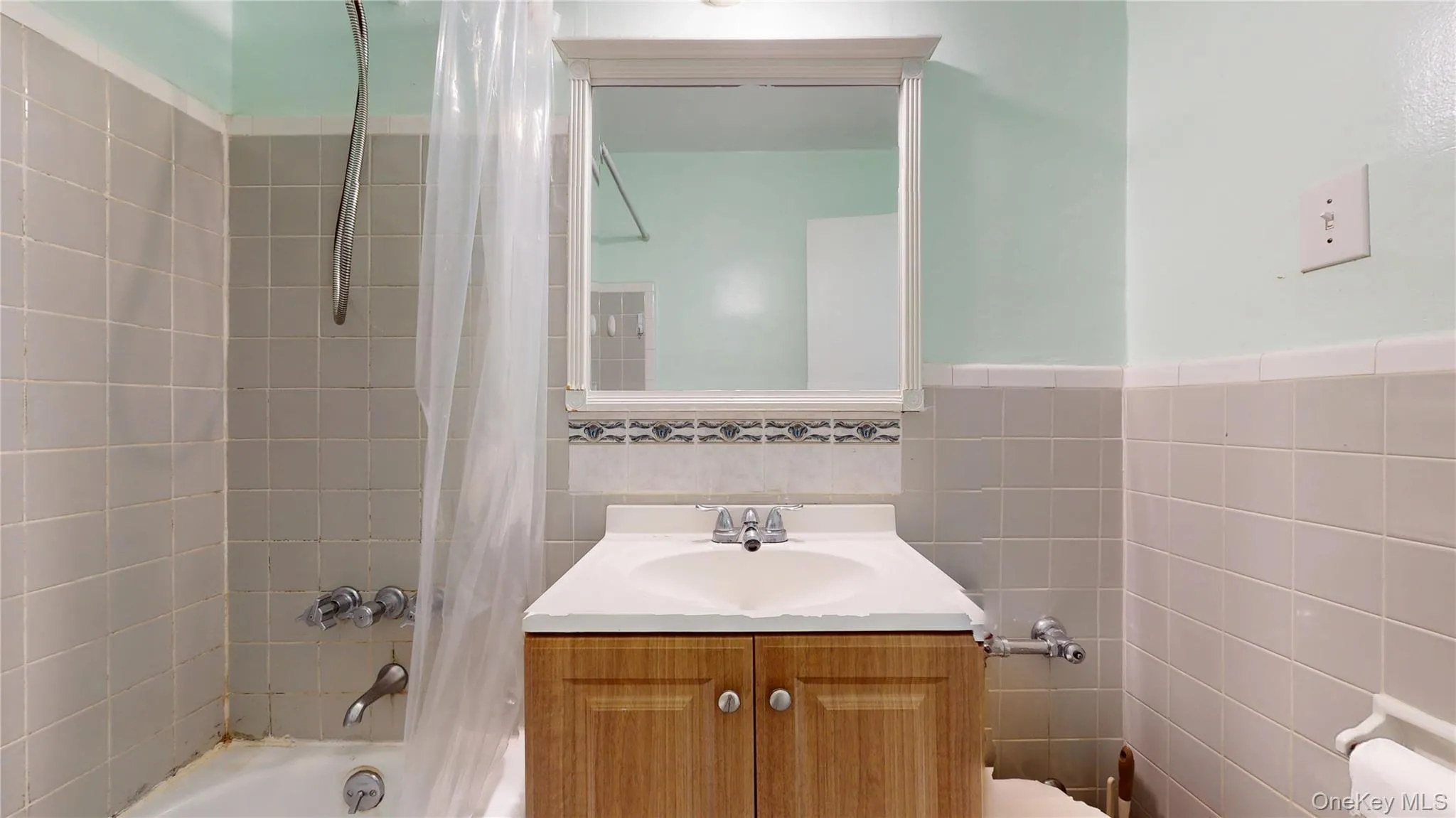 Full bathroom featuring shower / tub combo, vanity, and tile walls Full bathroom featuring shower / tub combo, vanity, and tile walls