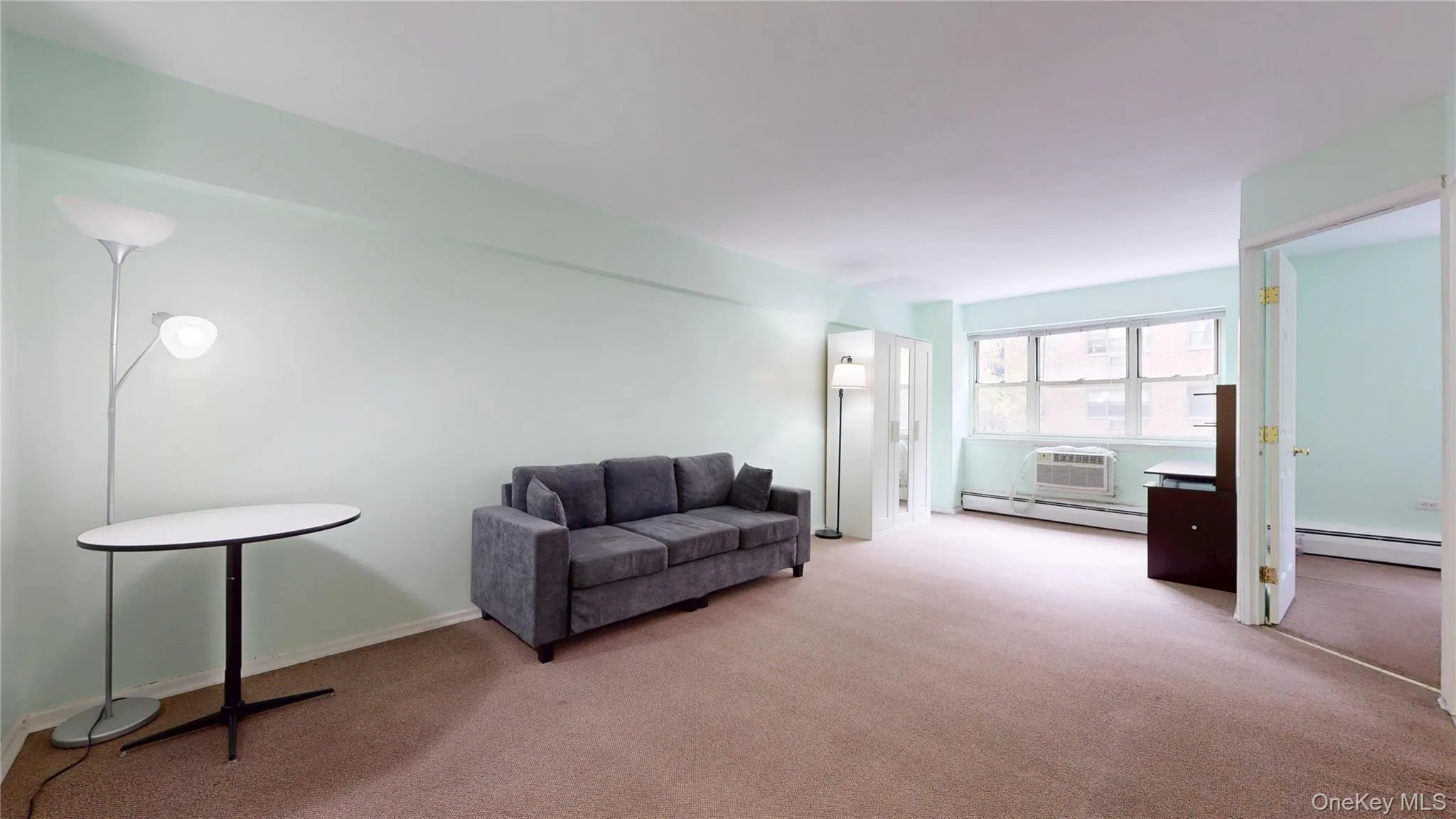 Living area with baseboard heating, carpet floors, and an AC wall unit Living area with baseboard heating, carpet floors, and an AC wall unit