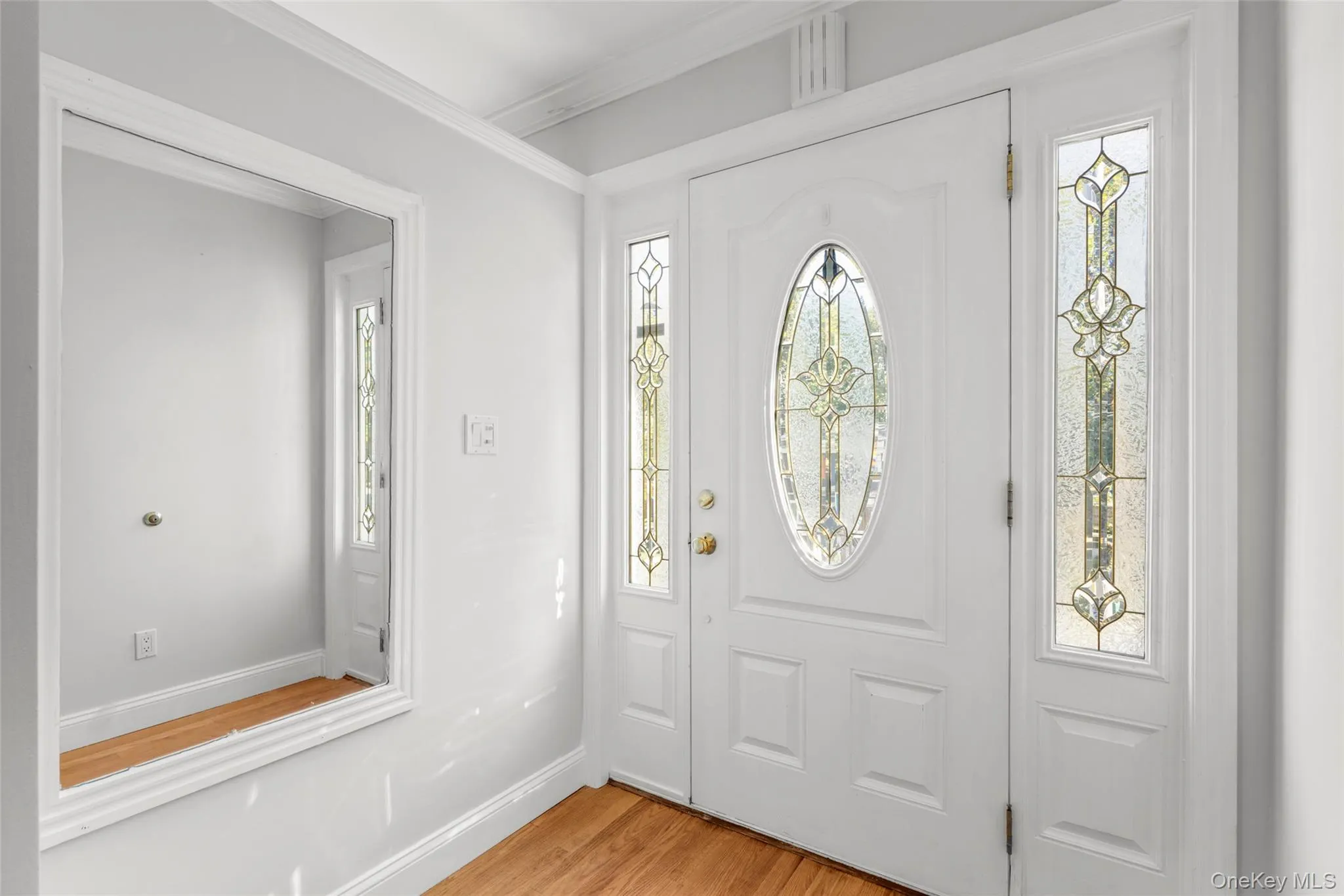 Entryway with light wood-style floors and ornamental molding Entryway with light wood-style floors and ornamental molding