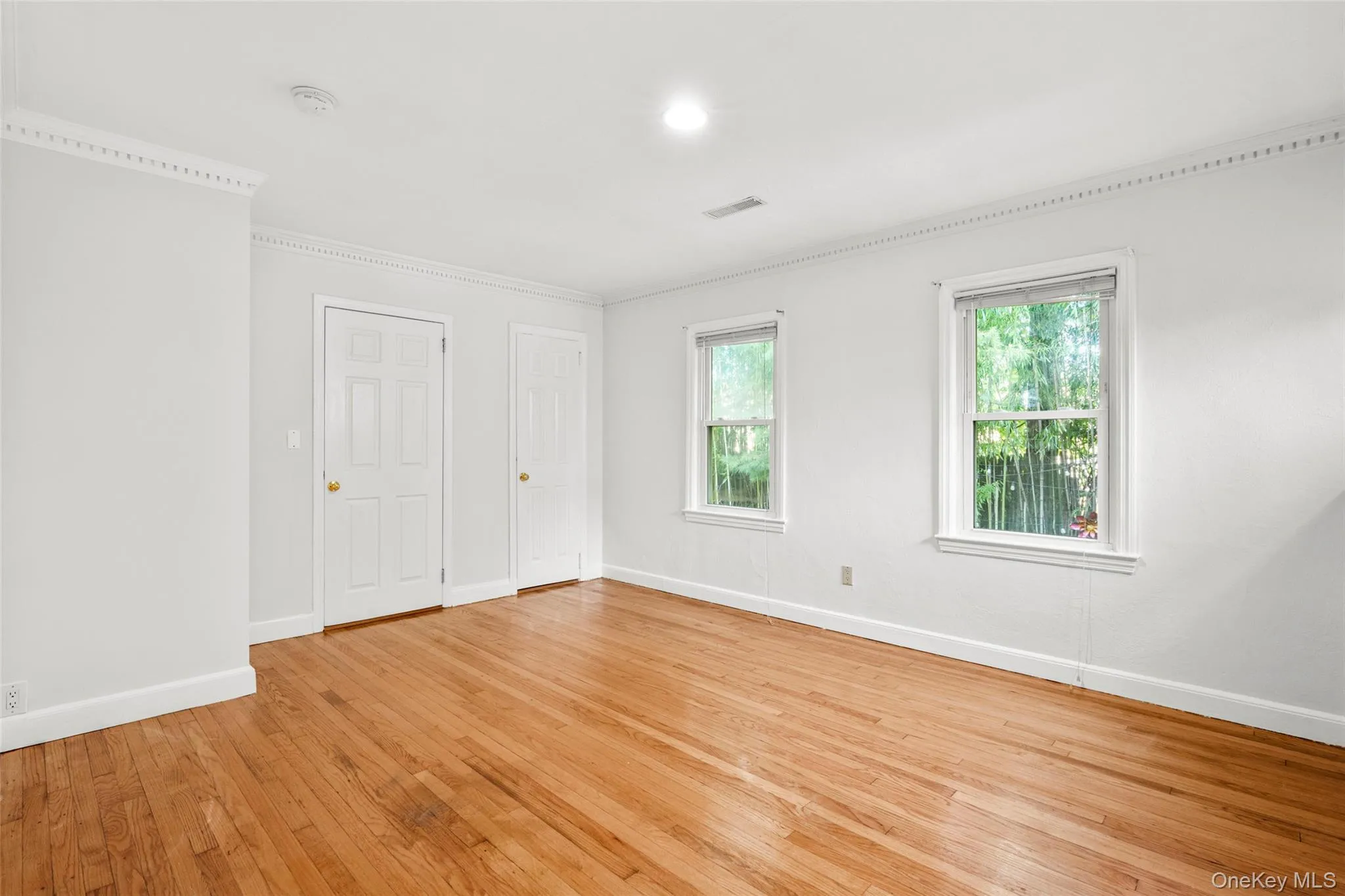 Unfurnished bedroom featuring light wood-type flooring, multiple closets, recessed lighting, and crown molding Unfurnished bedroom featuring light wood-type flooring, multiple closets, recessed lighting, and crown molding