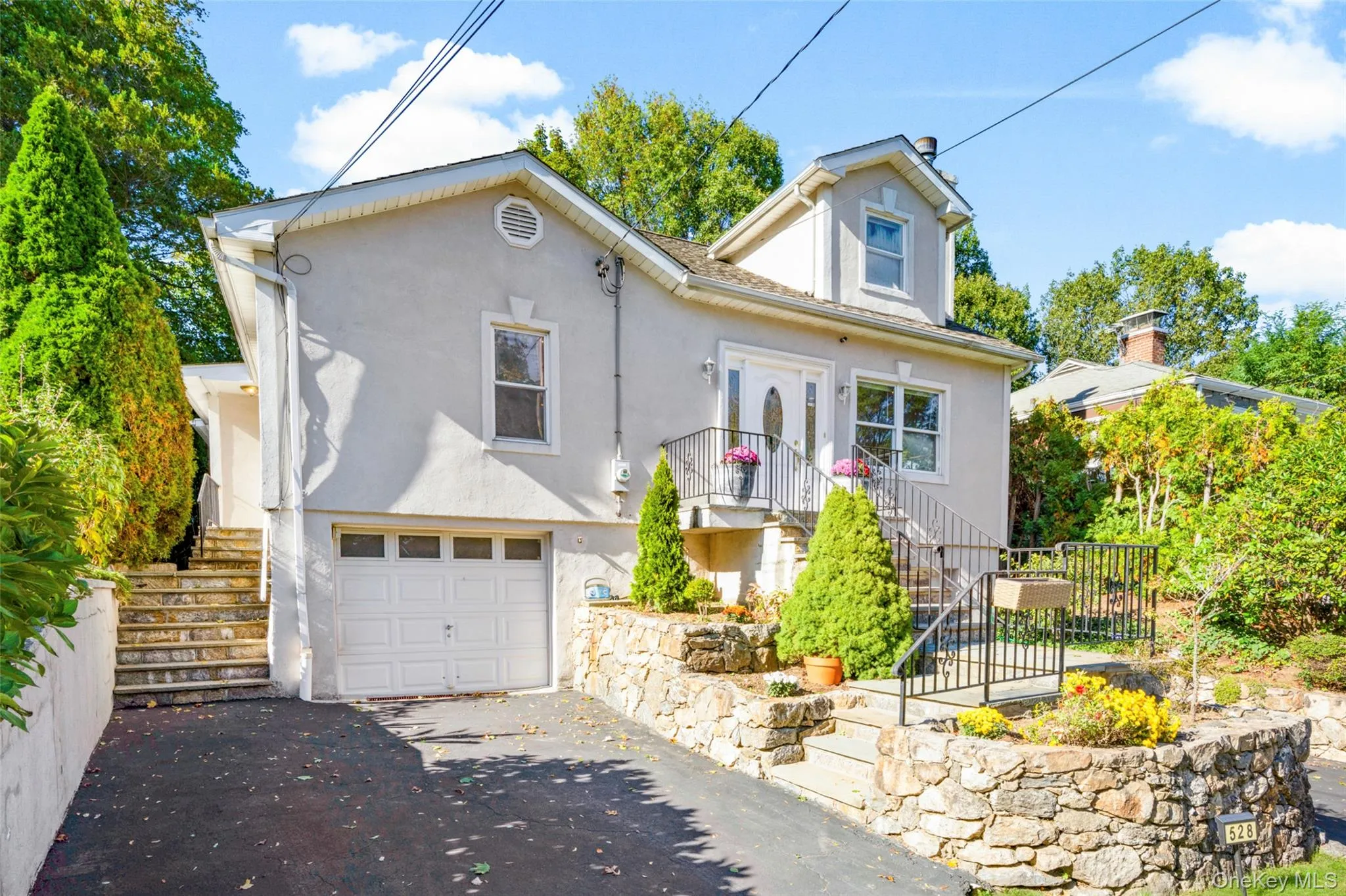 View of front of property with stairway, stucco siding, an attached garage, and driveway View of front of property with stairway, stucco siding, an attached garage, and driveway