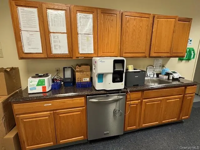 Kitchen with brown cabinets, stainless steel dishwasher, and dark stone countertops Kitchen with brown cabinets, stainless steel dishwasher, and dark stone countertops
