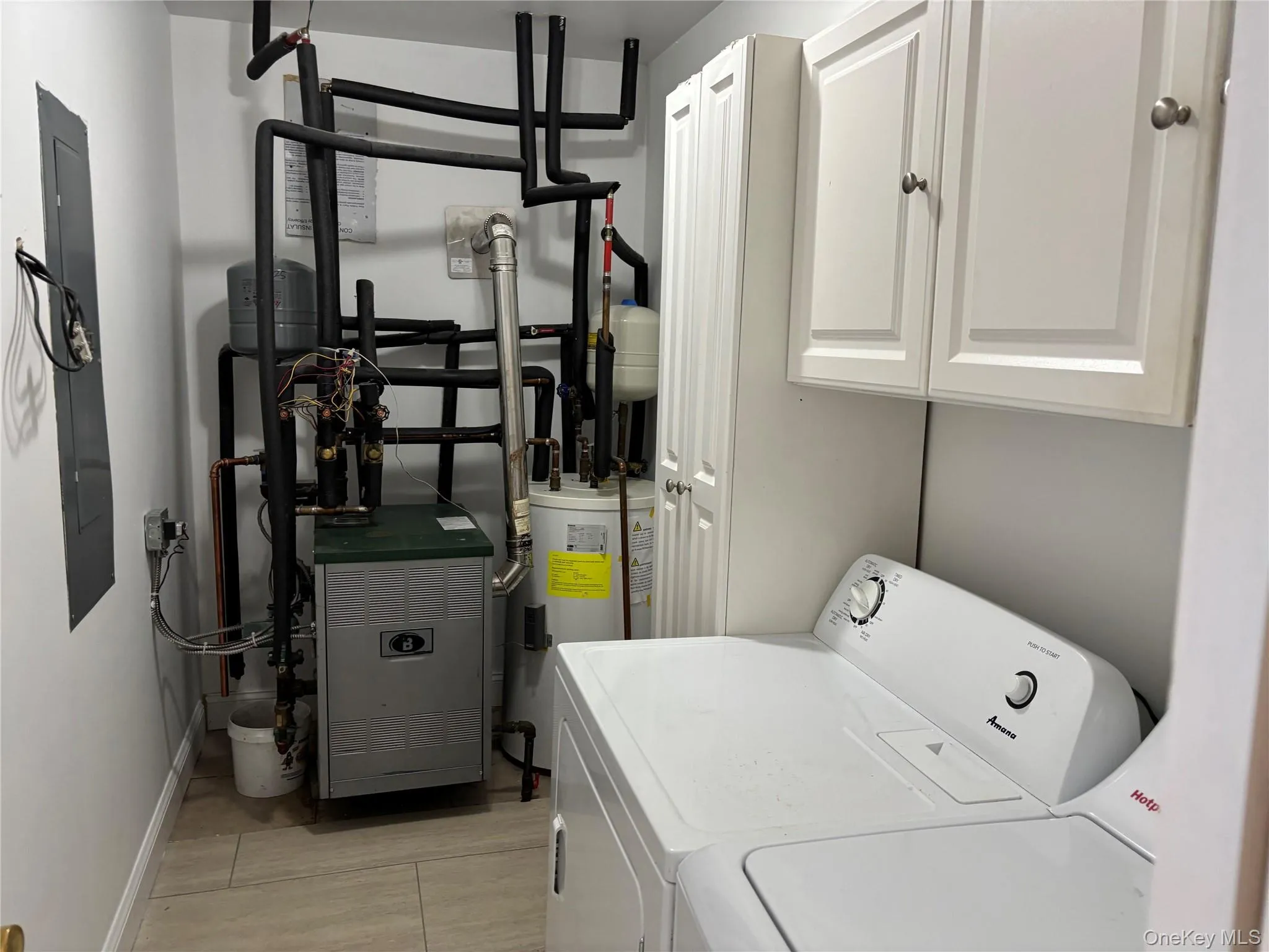 Washroom with independent washer and dryer, water heater, electric panel, cabinet space, and a heating unit Washroom with independent washer and dryer, water heater, electric panel, cabinet space, and a heating unit