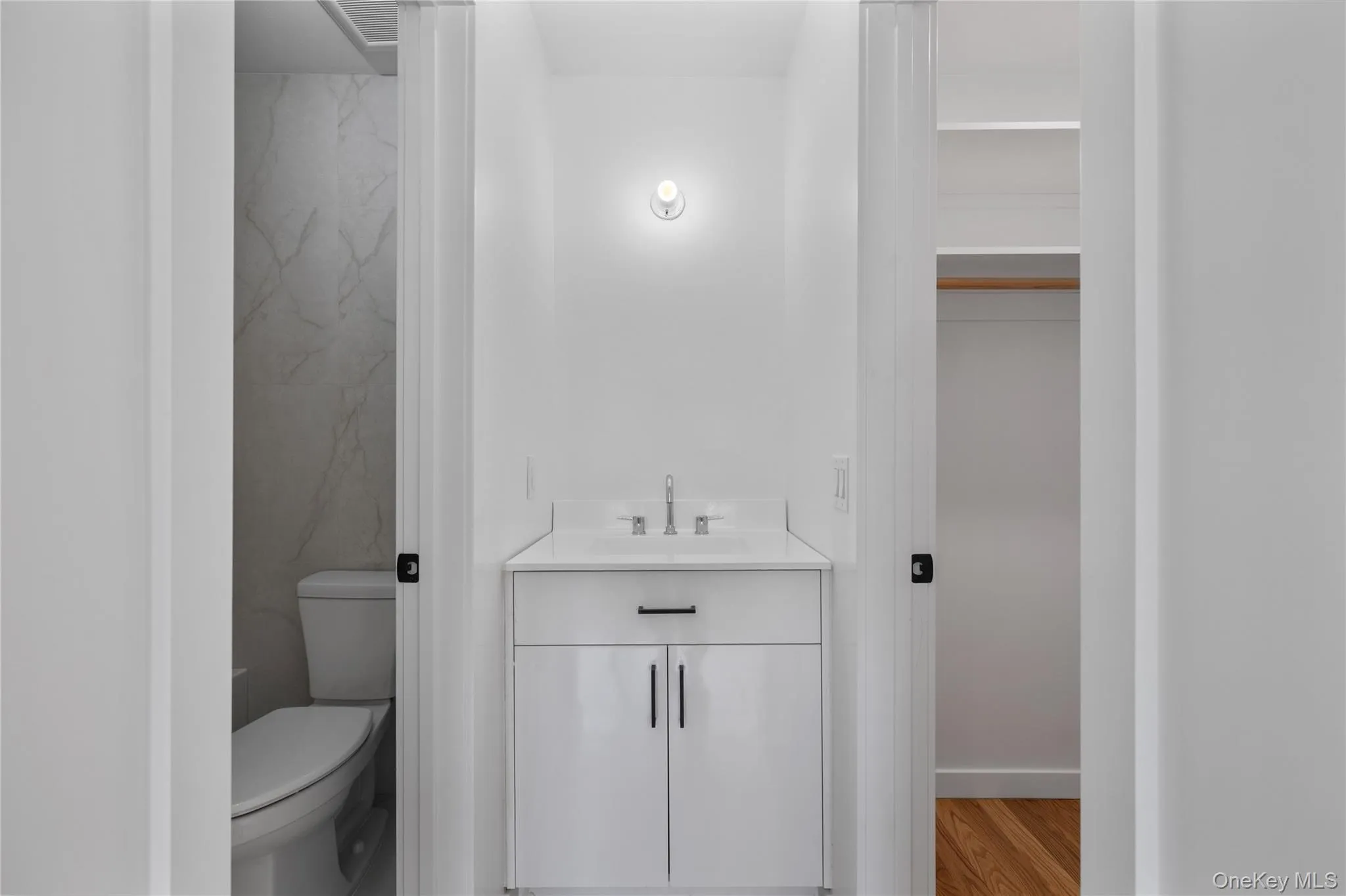 Bathroom featuring baseboards, wood finished floors, toilet, and vanity Bathroom featuring baseboards, wood finished floors, toilet, and vanity