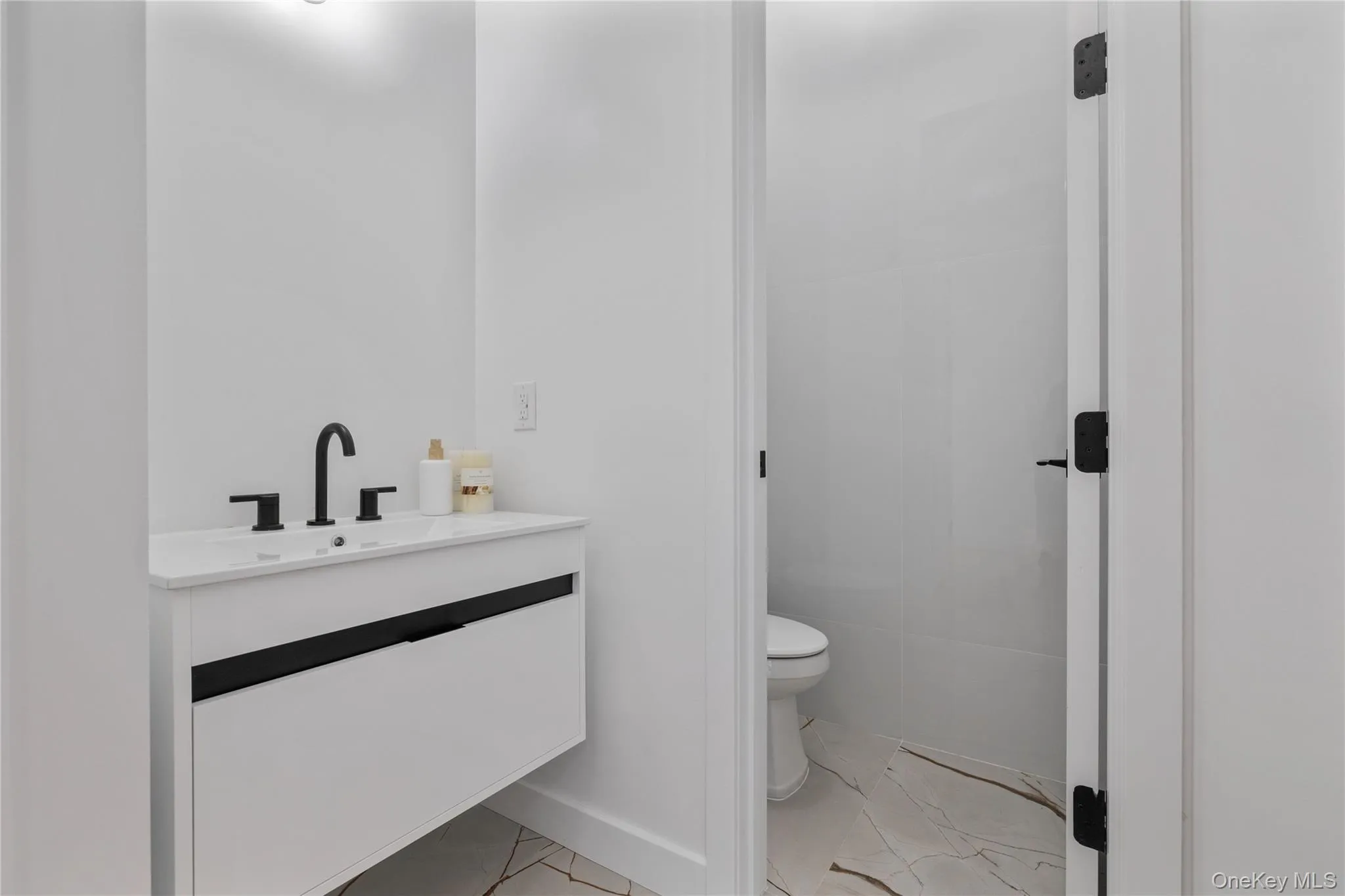 Bathroom with marble finish floor, toilet, vanity, and baseboards Bathroom with marble finish floor, toilet, vanity, and baseboards