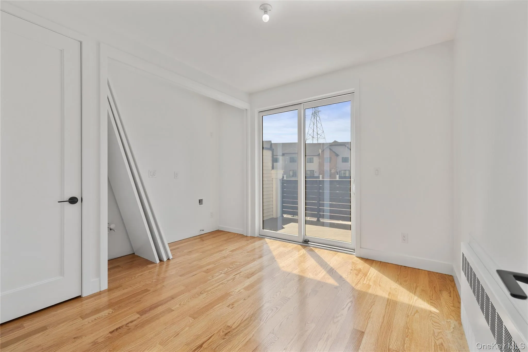 Spare room featuring radiator heating unit, light wood finished floors, and baseboards Spare room featuring radiator heating unit, light wood finished floors, and baseboards