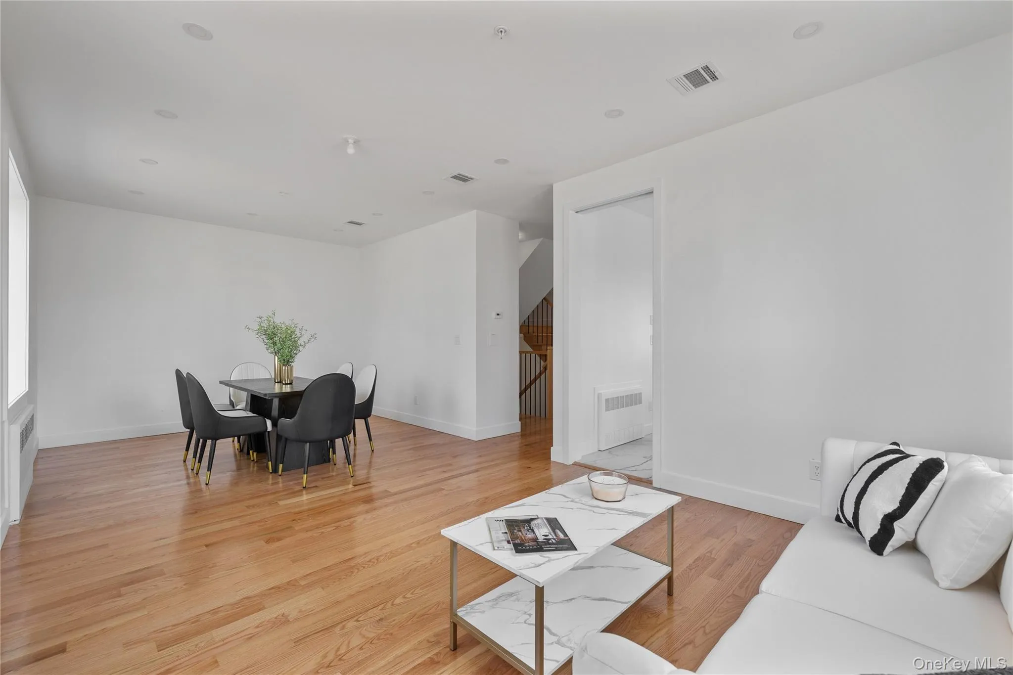 Living room with light wood-style flooring, visible vents, and baseboards Living room with light wood-style flooring, visible vents, and baseboards