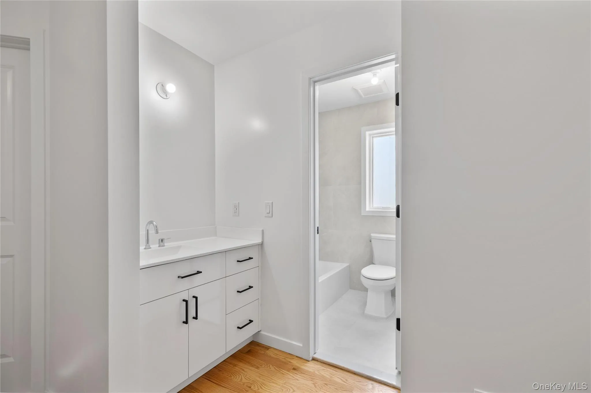 Full bathroom with a bath, toilet, baseboards, wood finished floors, and vanity Full bathroom with a bath, toilet, baseboards, wood finished floors, and vanity