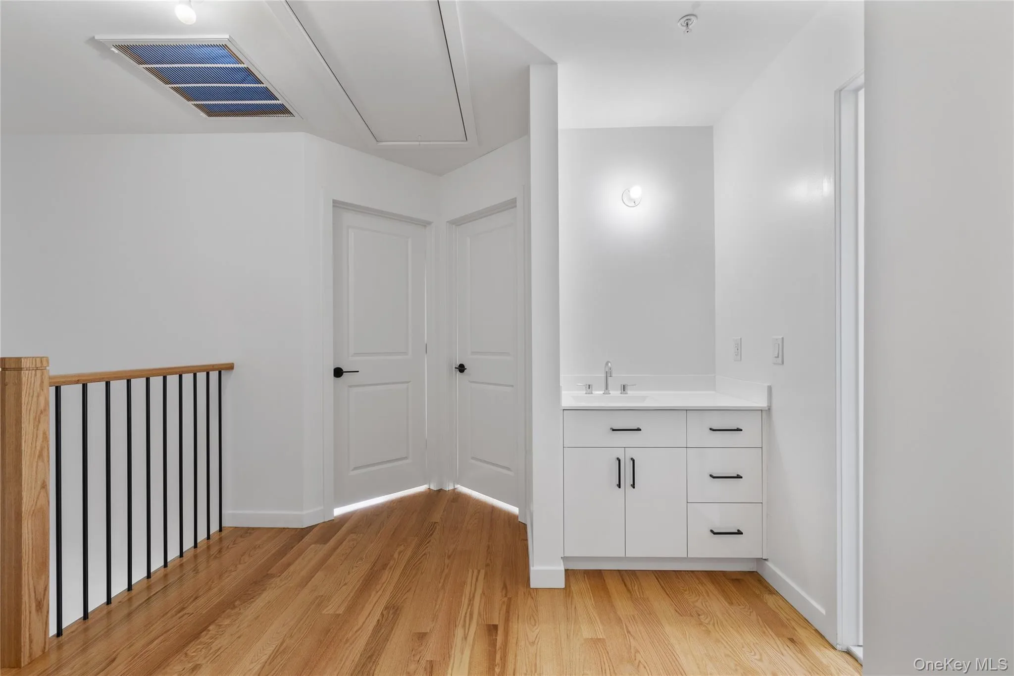 Hall with light wood finished floors, attic access, a sink, baseboards, and visible vents Hall with light wood finished floors, attic access, a sink, baseboards, and visible vents