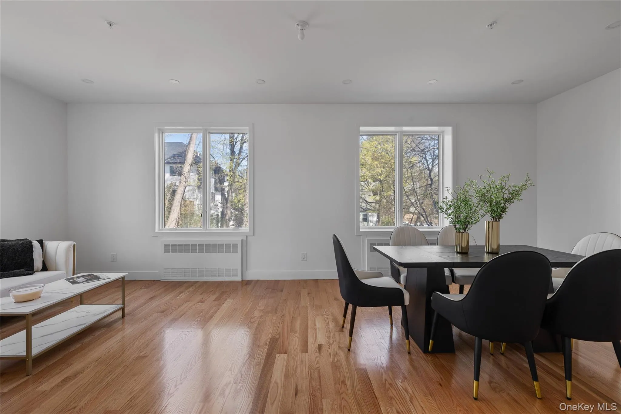 Dining area featuring baseboards, radiator heating unit, light wood-type flooring, and plenty of natural light Dining area featuring baseboards, radiator heating unit, light wood-type flooring, and plenty of natural light