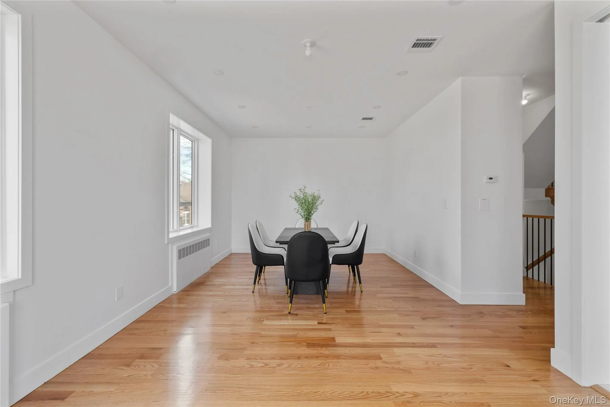 Dining room with radiator, light wood-style flooring, visible vents, and baseboards Dining room with radiator, light wood-style flooring, visible vents, and baseboards