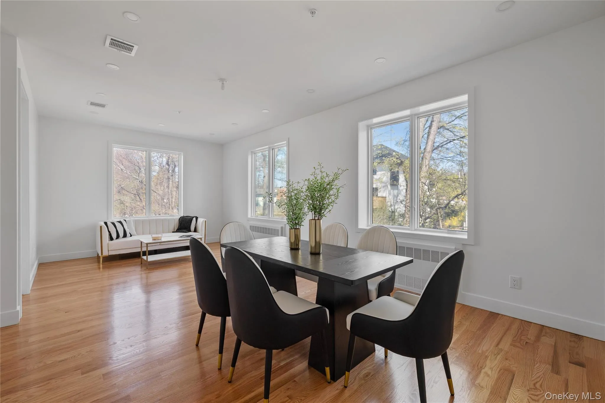 Dining space with radiator, baseboards, light wood-style floors, and visible vents Dining space with radiator, baseboards, light wood-style floors, and visible vents
