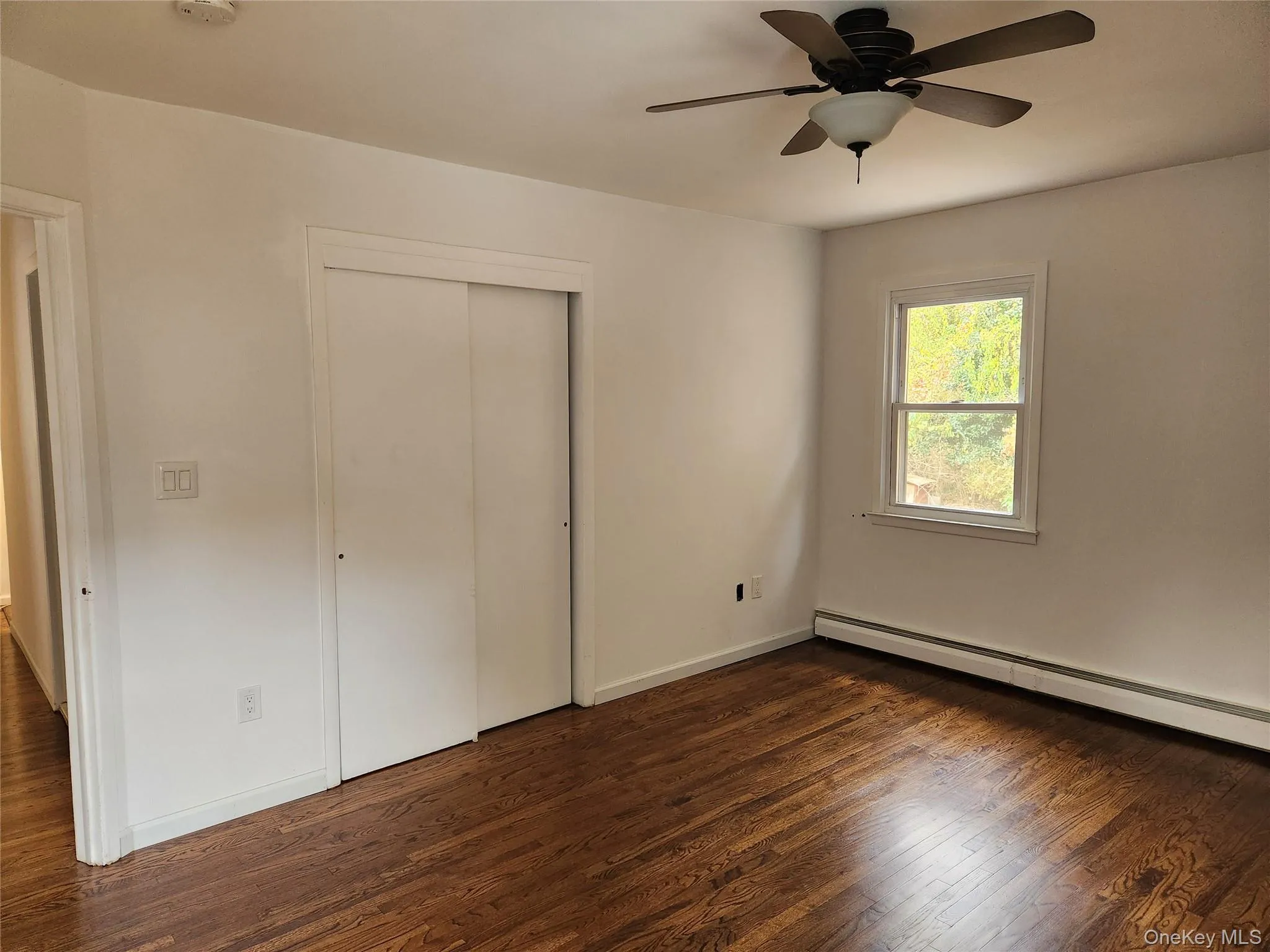 Bedroom featuring Hard wood floors, a closet, ceiling fan, and baseboard heating Bedroom featuring Hard wood floors, a closet, ceiling fan, and baseboard heating