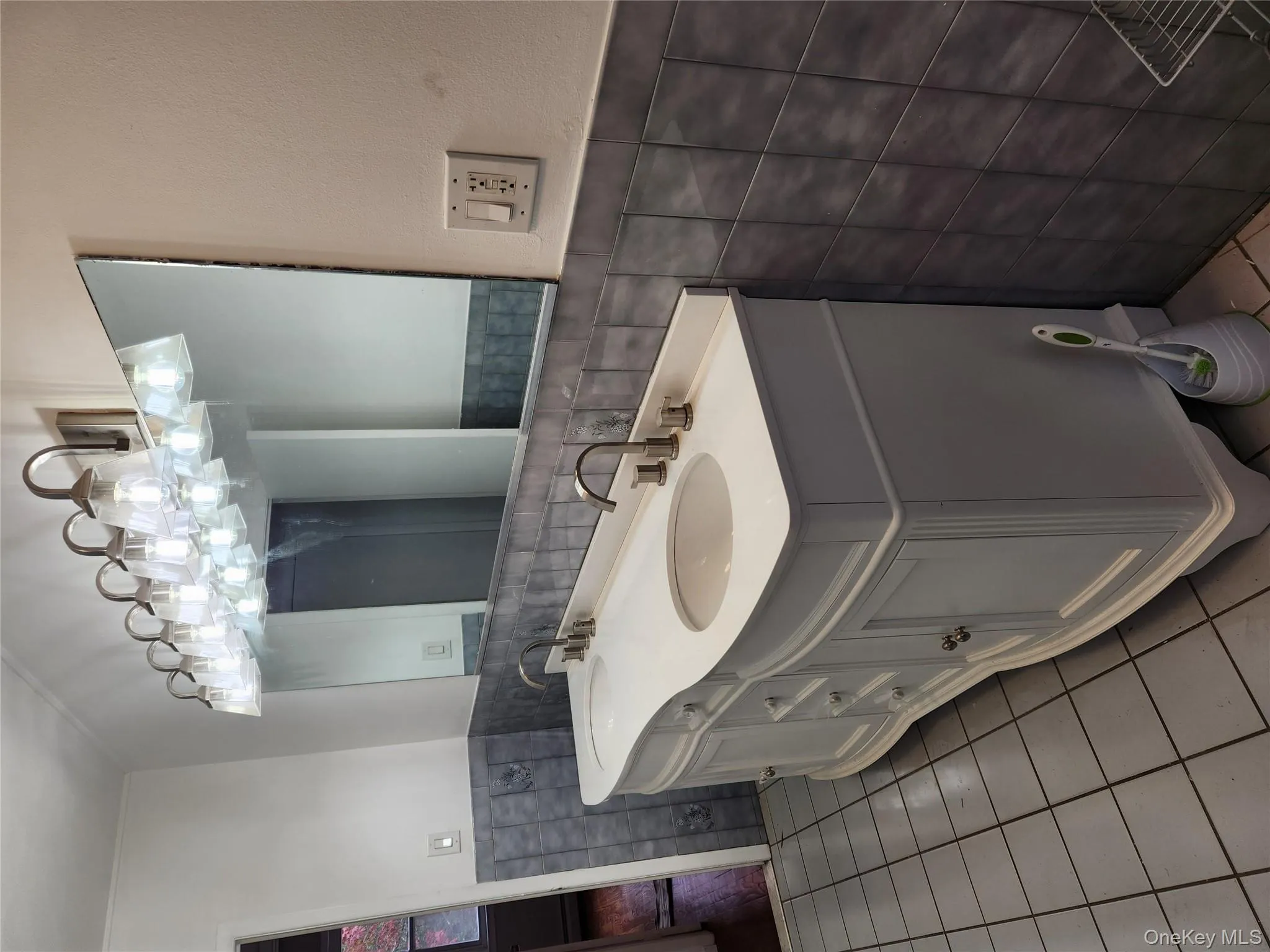 Full bathroom featuring tile walls, light tile patterned floors, wainscoting, and double vanity Full bathroom featuring tile walls, light tile patterned floors, wainscoting, and double vanity