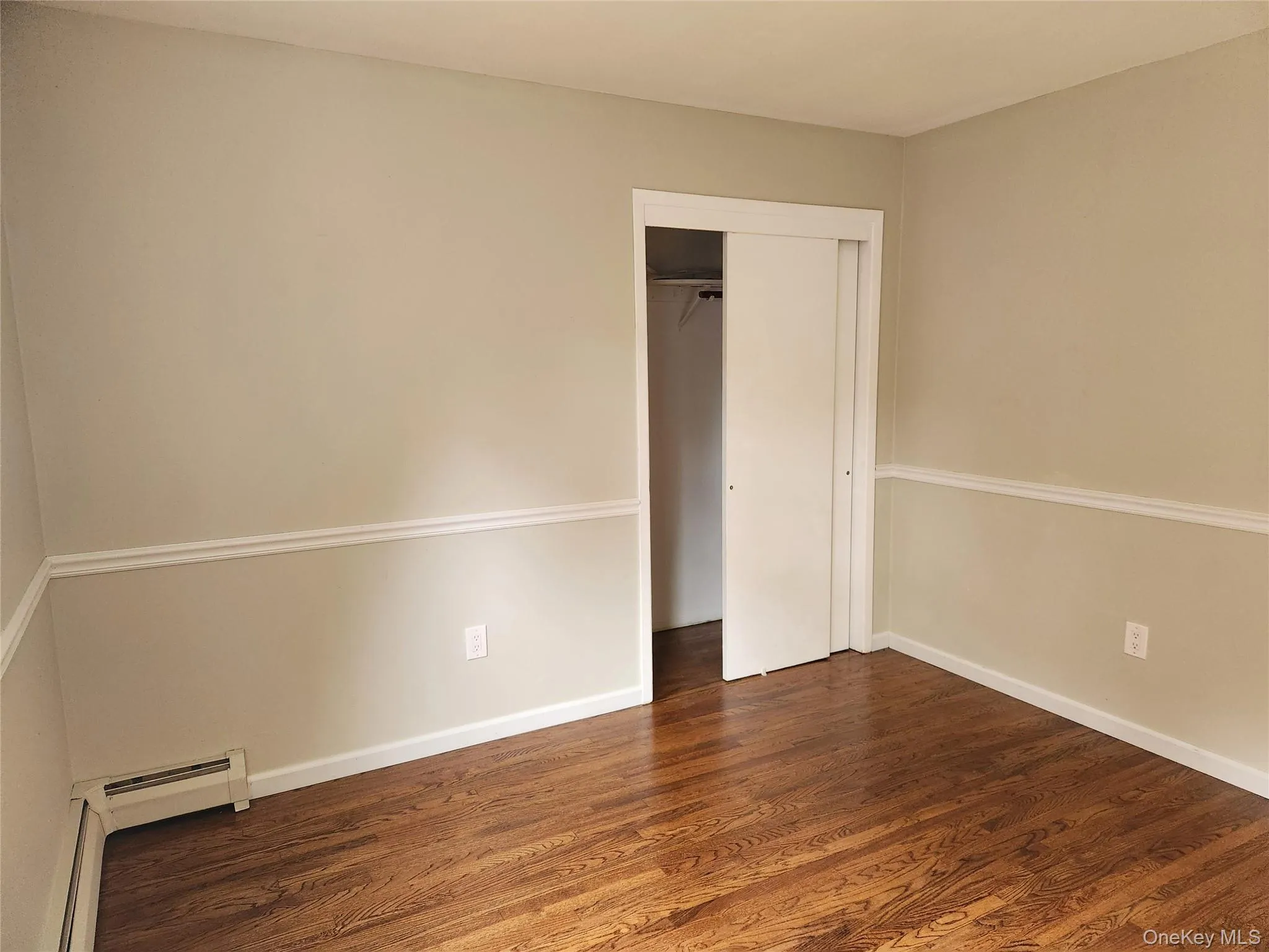 Bedroom with Hardwood Flooring, baseboard heating unit, and a closet Bedroom with Hardwood Flooring, baseboard heating unit, and a closet