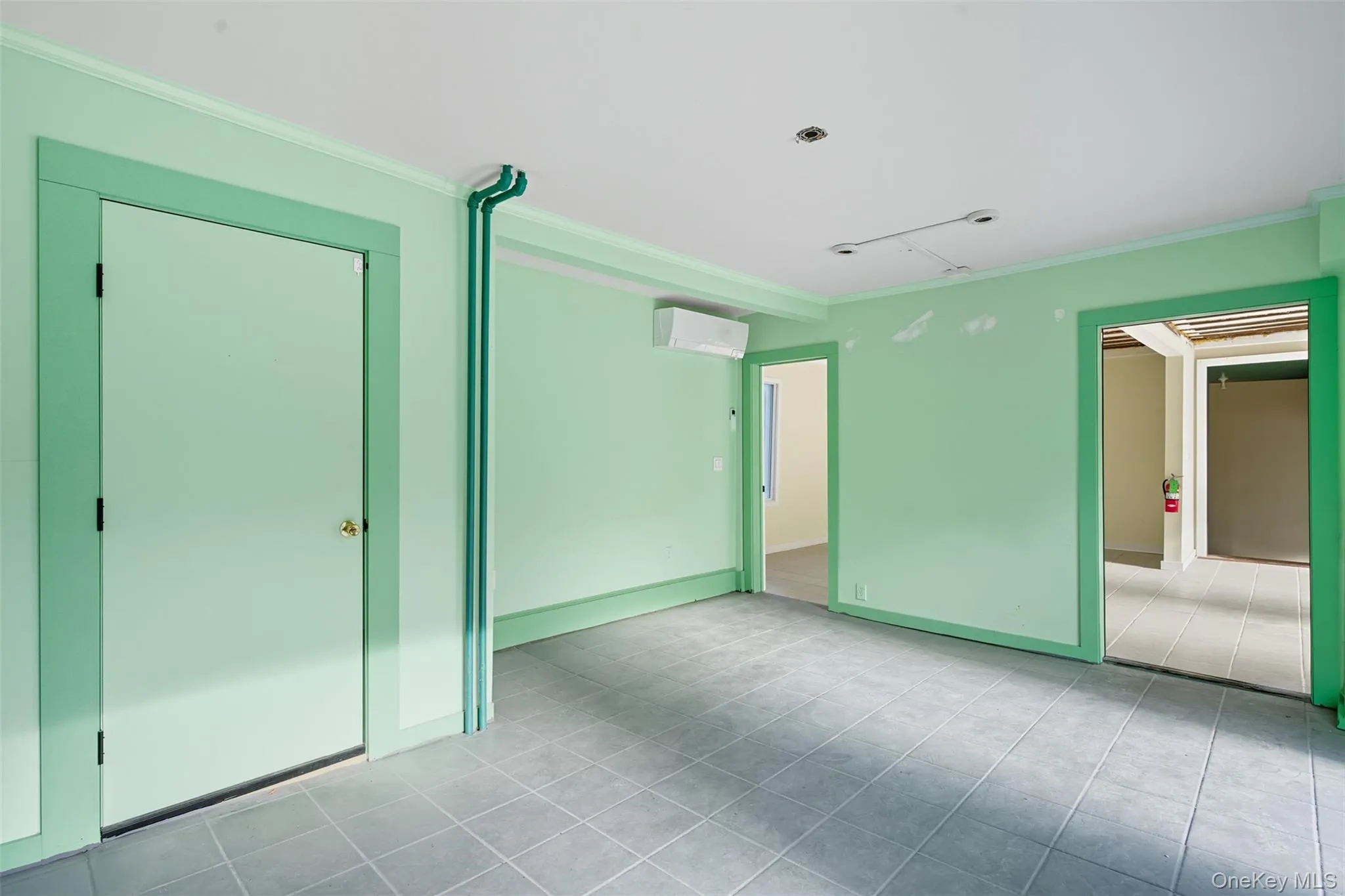 Unfurnished bedroom with ornamental molding, light tile patterned floors, an AC wall unit, and a closet Unfurnished bedroom with ornamental molding, light tile patterned floors, an AC wall unit, and a closet