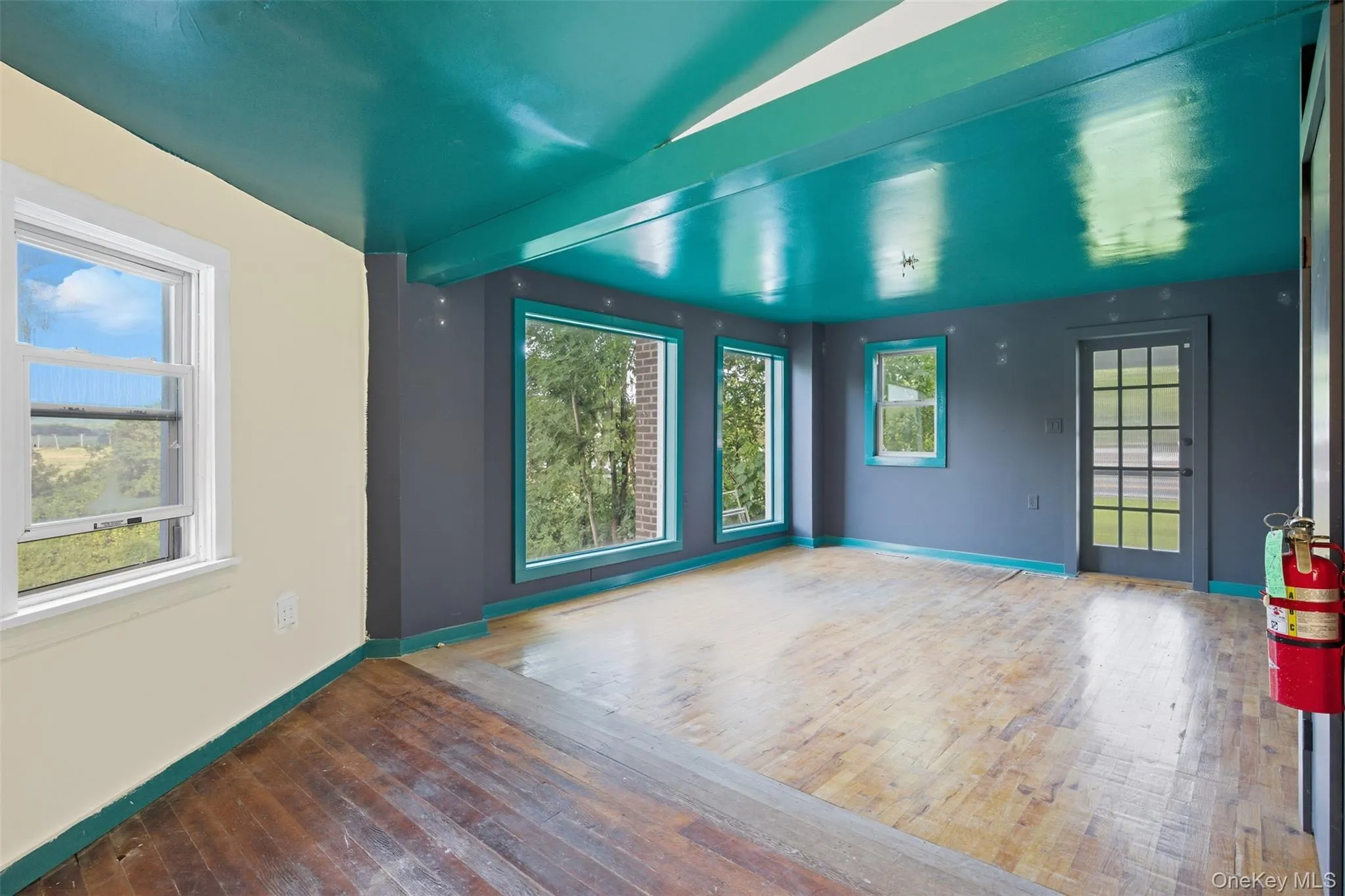 Empty room featuring wood-type flooring, healthy amount of natural light, and beam ceiling Empty room featuring wood-type flooring, healthy amount of natural light, and beam ceiling