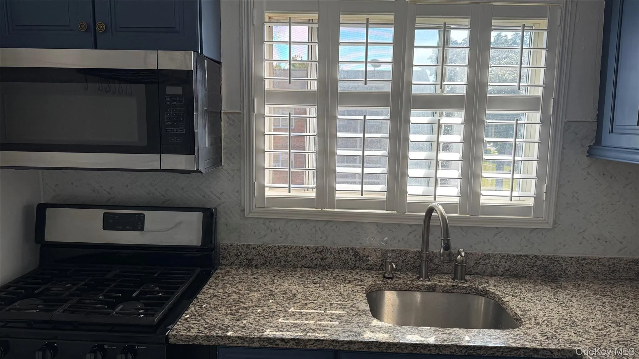 Kitchen featuring appliances with stainless steel finishes, dark stone counters, and blue cabinetry Kitchen featuring appliances with stainless steel finishes, dark stone counters, and blue cabinetry