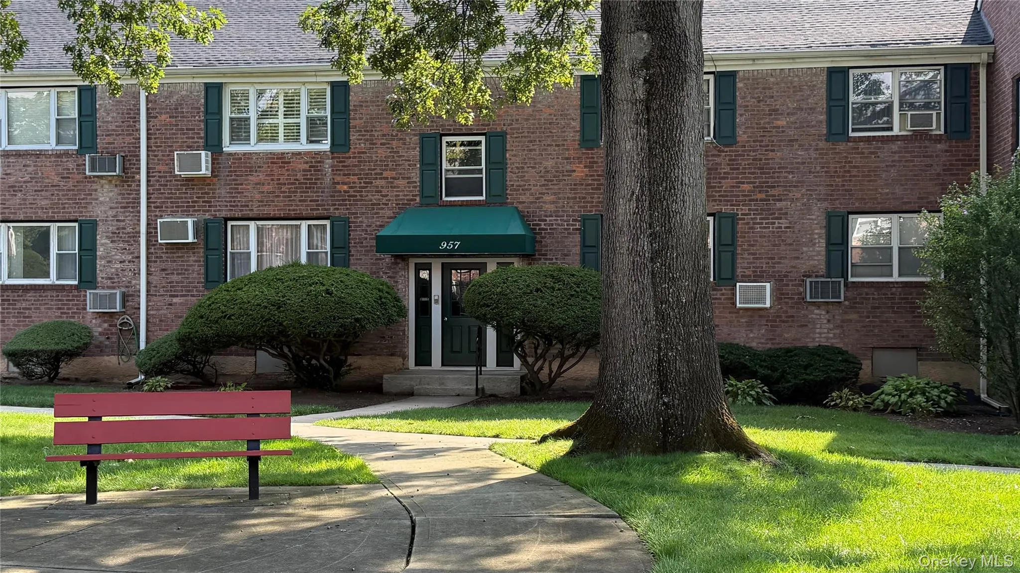 View of front facade with brick siding, a front yard, and a wall unit AC View of front facade with brick siding, a front yard, and a wall unit AC