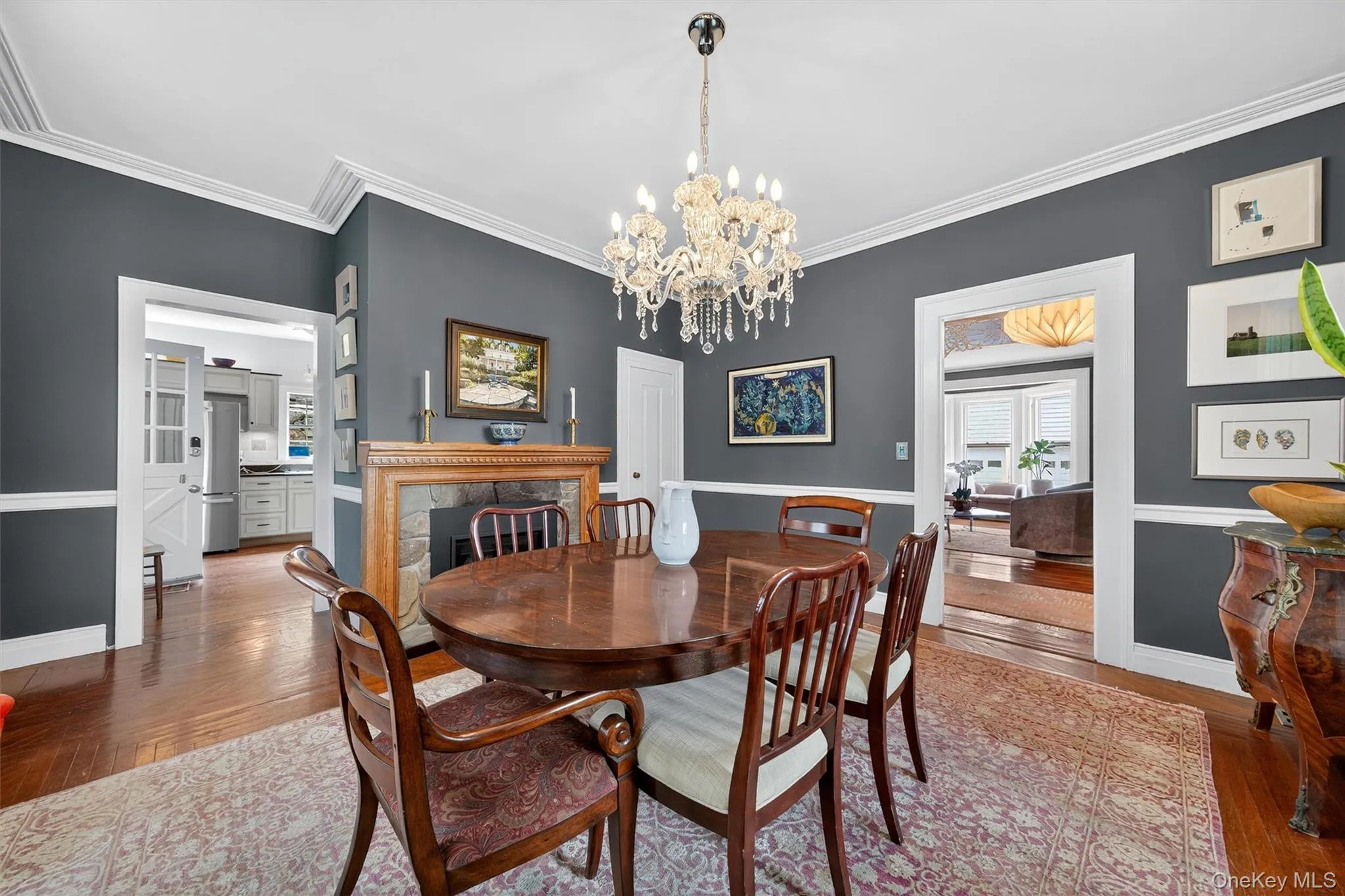 Dining room with hardwood / wood-style floors, a chandelier, ornamental molding, and a premium fireplace Dining room with hardwood / wood-style floors, a chandelier, ornamental molding, and a premium fireplace