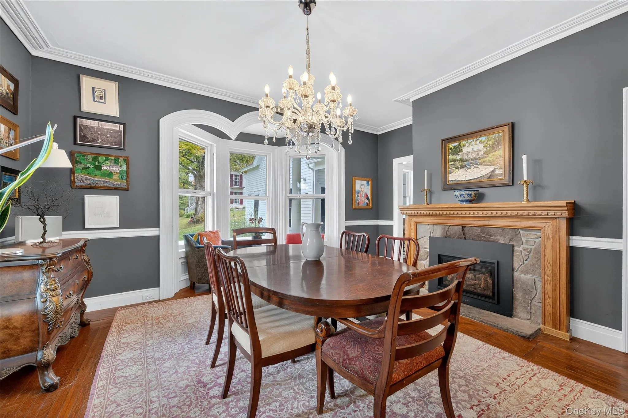 Dining area featuring wood finished floors, a fireplace, a chandelier, and crown molding Dining area featuring wood finished floors, a fireplace, a chandelier, and crown molding