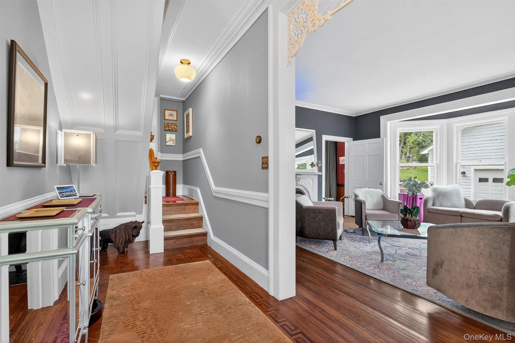 Entryway with a decorative wall, dark wood-style floors, crown molding, and stairs Entryway with a decorative wall, dark wood-style floors, crown molding, and stairs