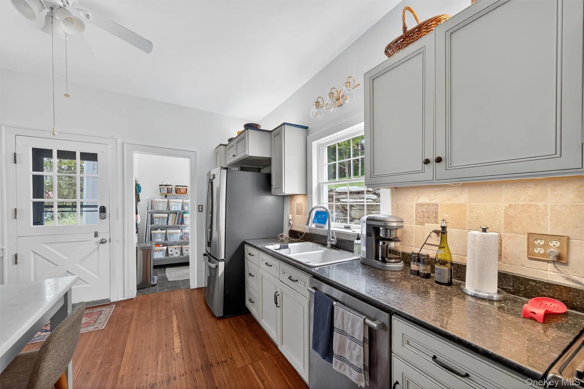 Kitchen featuring appliances with stainless steel finishes, dark wood-type flooring, gray cabinets, backsplash, and a ceiling fan Kitchen featuring appliances with stainless steel finishes, dark wood-type flooring, gray cabinets, backsplash, and a ceiling fan