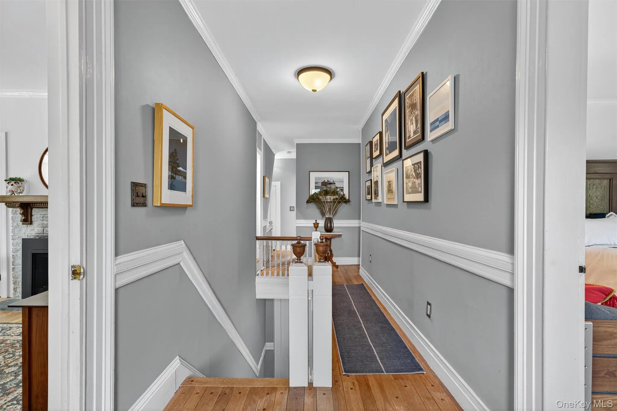 Corridor featuring light wood-style floors, crown molding, and an upstairs landing Corridor featuring light wood-style floors, crown molding, and an upstairs landing