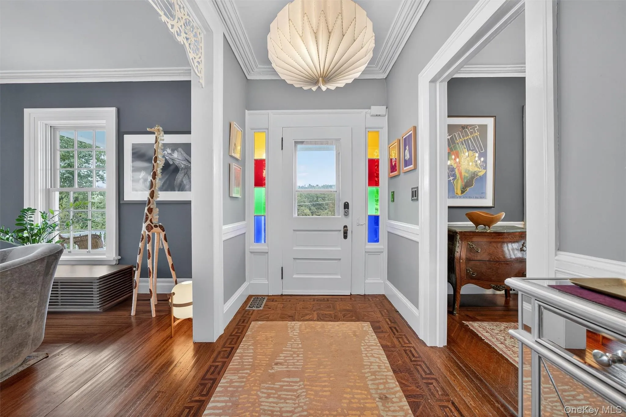 Foyer entrance featuring ornamental molding, dark wood-style floors, a wainscoted wall, and a decorative wall Foyer entrance featuring ornamental molding, dark wood-style floors, a wainscoted wall, and a decorative wall