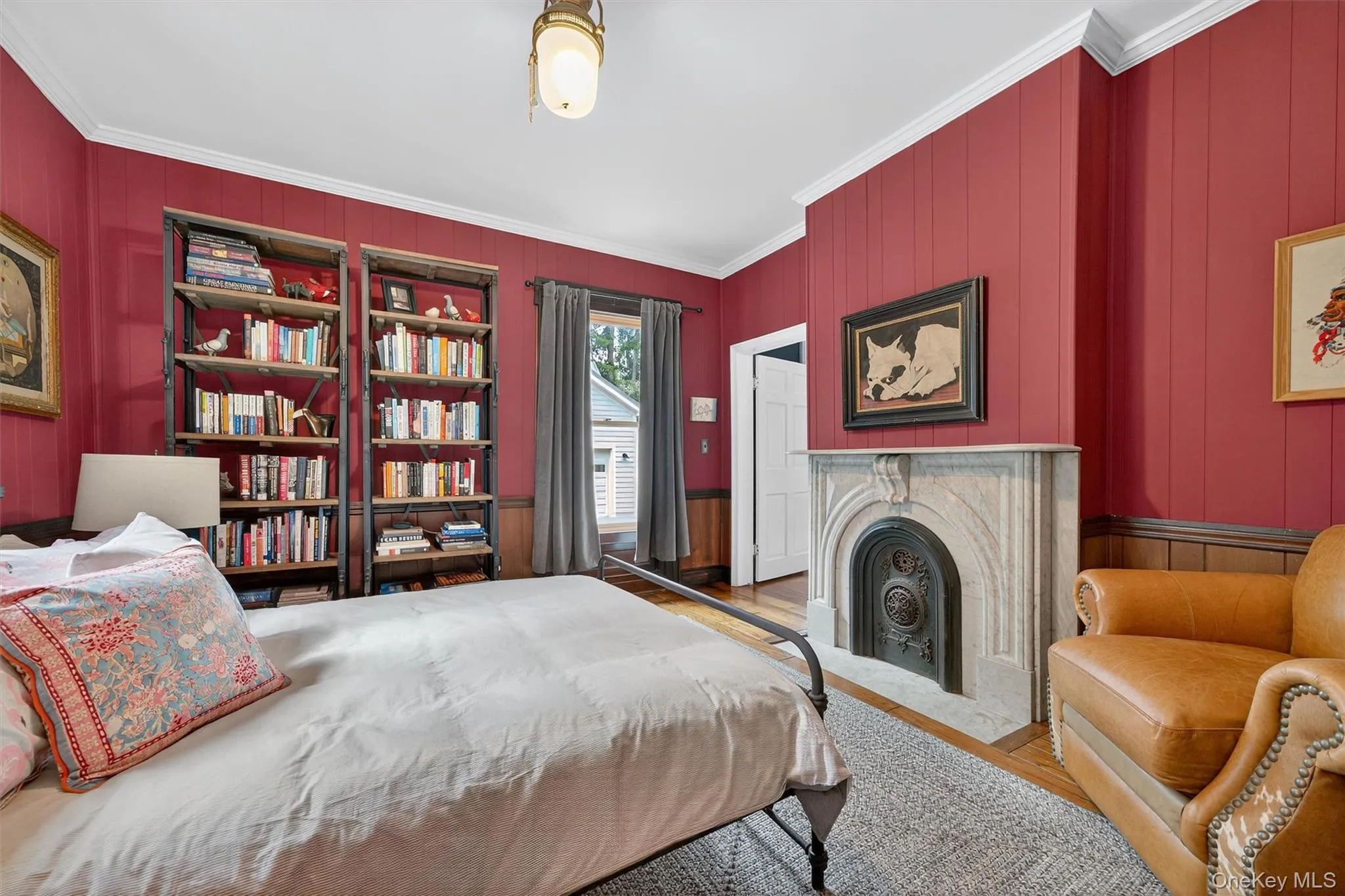 Bedroom featuring crown molding, wood walls, wood finished floors, and a fireplace with flush hearth Bedroom featuring crown molding, wood walls, wood finished floors, and a fireplace with flush hearth
