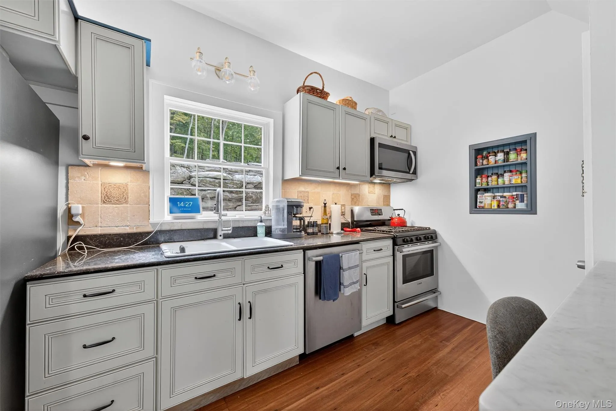 Kitchen with dark wood-style flooring, stainless steel appliances, and decorative backsplash Kitchen with dark wood-style flooring, stainless steel appliances, and decorative backsplash
