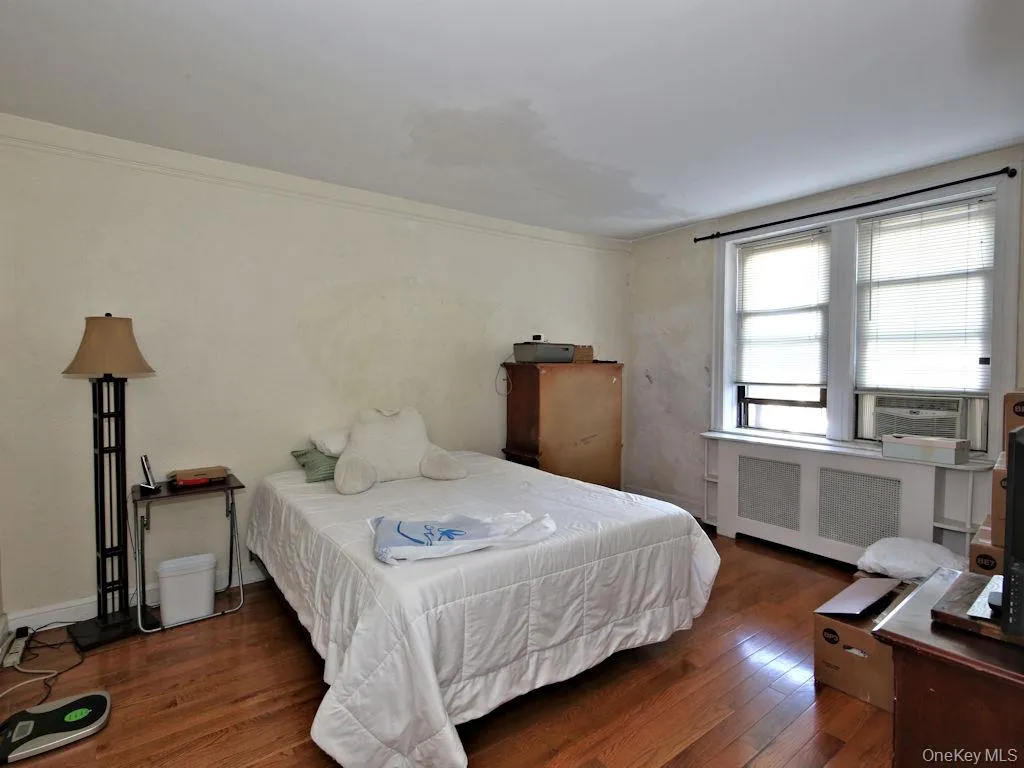 Bedroom with dark wood finished floors, radiator, and cooling unit Bedroom with dark wood finished floors, radiator, and cooling unit