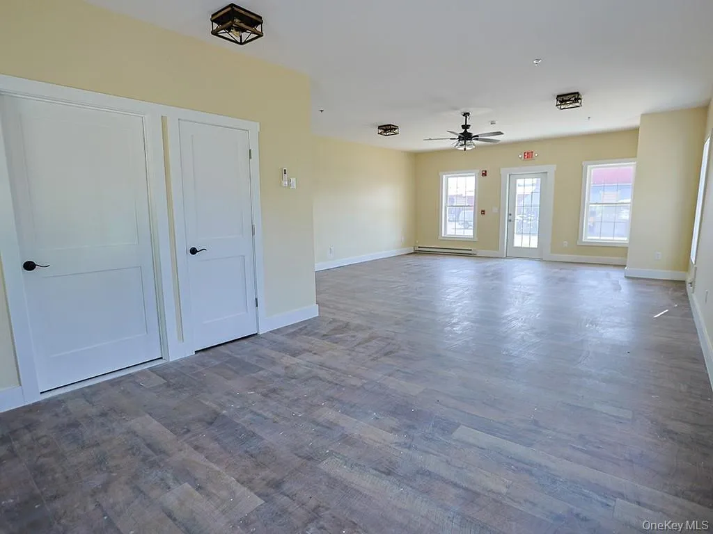 Empty room featuring wood finished floors, ceiling fan, and a baseboard heating unit Empty room featuring wood finished floors, ceiling fan, and a baseboard heating unit
