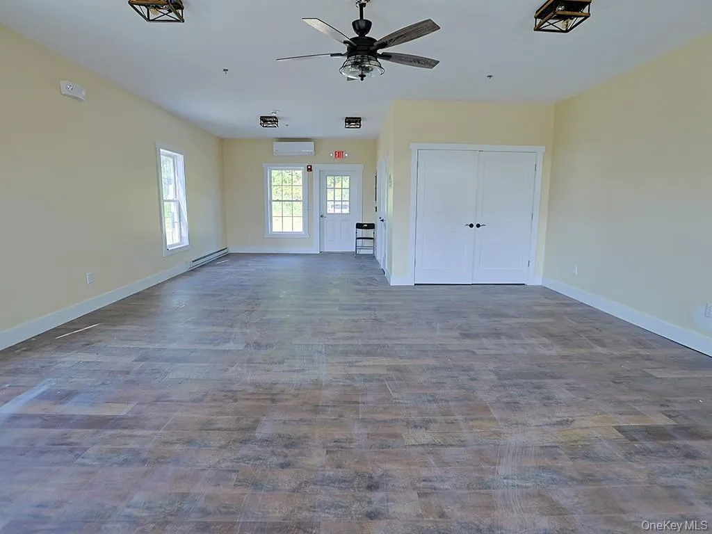 Unfurnished living room with dark wood-style flooring, baseboard heating, and a ceiling fan Unfurnished living room with dark wood-style flooring, baseboard heating, and a ceiling fan