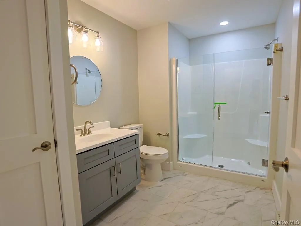 Full bathroom with a stall shower, vanity, light marble finish flooring, and recessed lighting Full bathroom with a stall shower, vanity, light marble finish flooring, and recessed lighting
