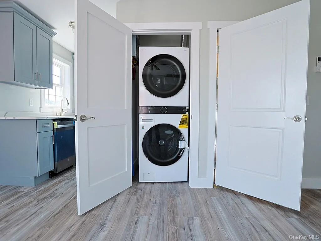 Washroom featuring stacked washer / drying machine and light wood-type flooring Washroom featuring stacked washer / drying machine and light wood-type flooring
