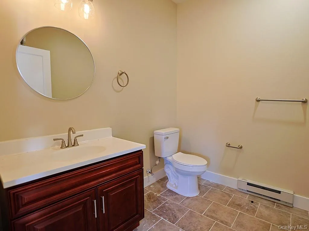 Bathroom with a baseboard heating unit, vanity, and light tile patterned flooring Bathroom with a baseboard heating unit, vanity, and light tile patterned flooring