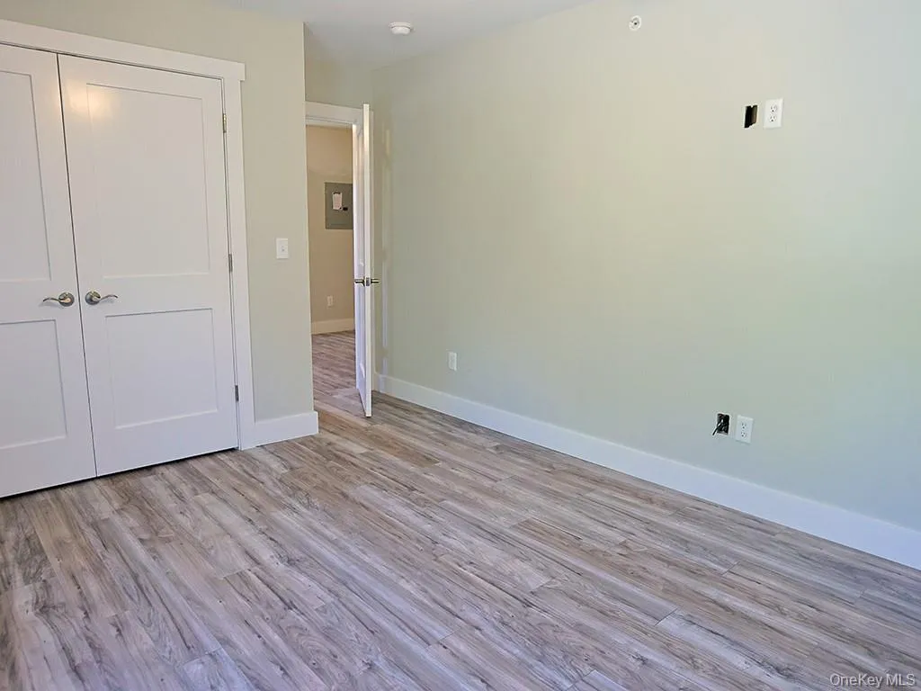 Unfurnished bedroom with a closet, light wood-type flooring, and electric panel Unfurnished bedroom with a closet, light wood-type flooring, and electric panel