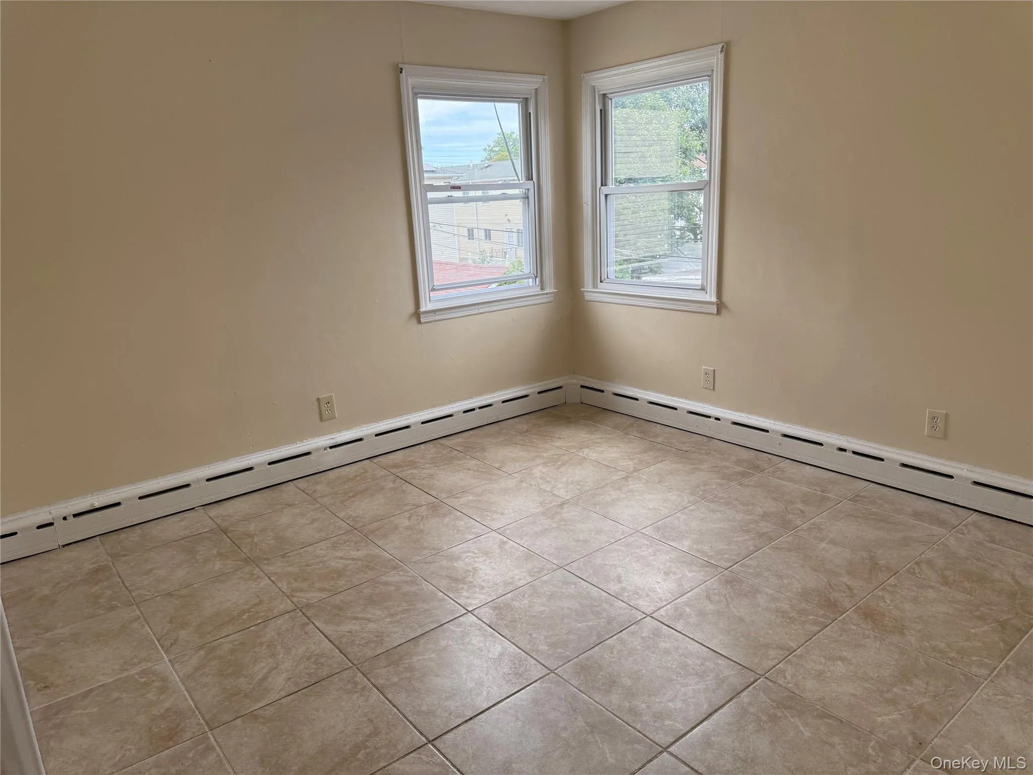 Unfurnished room featuring a baseboard radiator and light tile patterned floors Unfurnished room featuring a baseboard radiator and light tile patterned floors