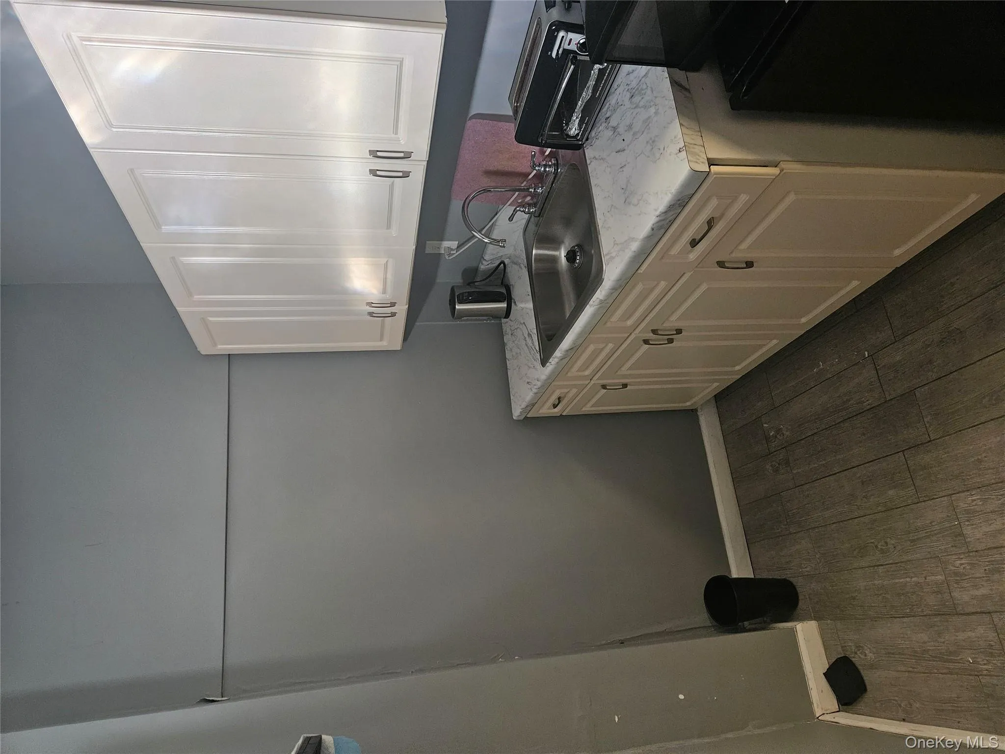 Kitchen with light countertops, dark wood-style floors, and white cabinets Kitchen with light countertops, dark wood-style floors, and white cabinets