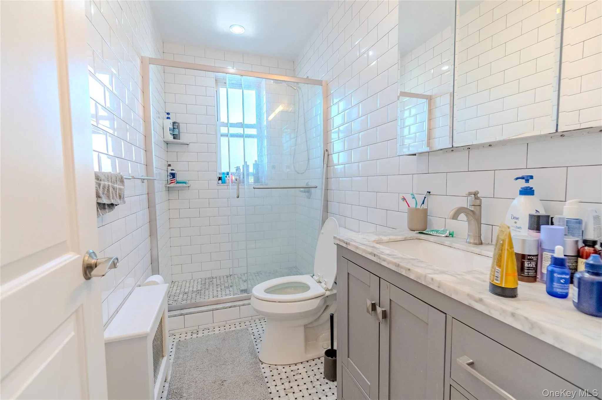 Bathroom featuring tile walls, vanity, a stall shower, light tile patterned floors, and tasteful backsplash Bathroom featuring tile walls, vanity, a stall shower, light tile patterned floors, and tasteful backsplash