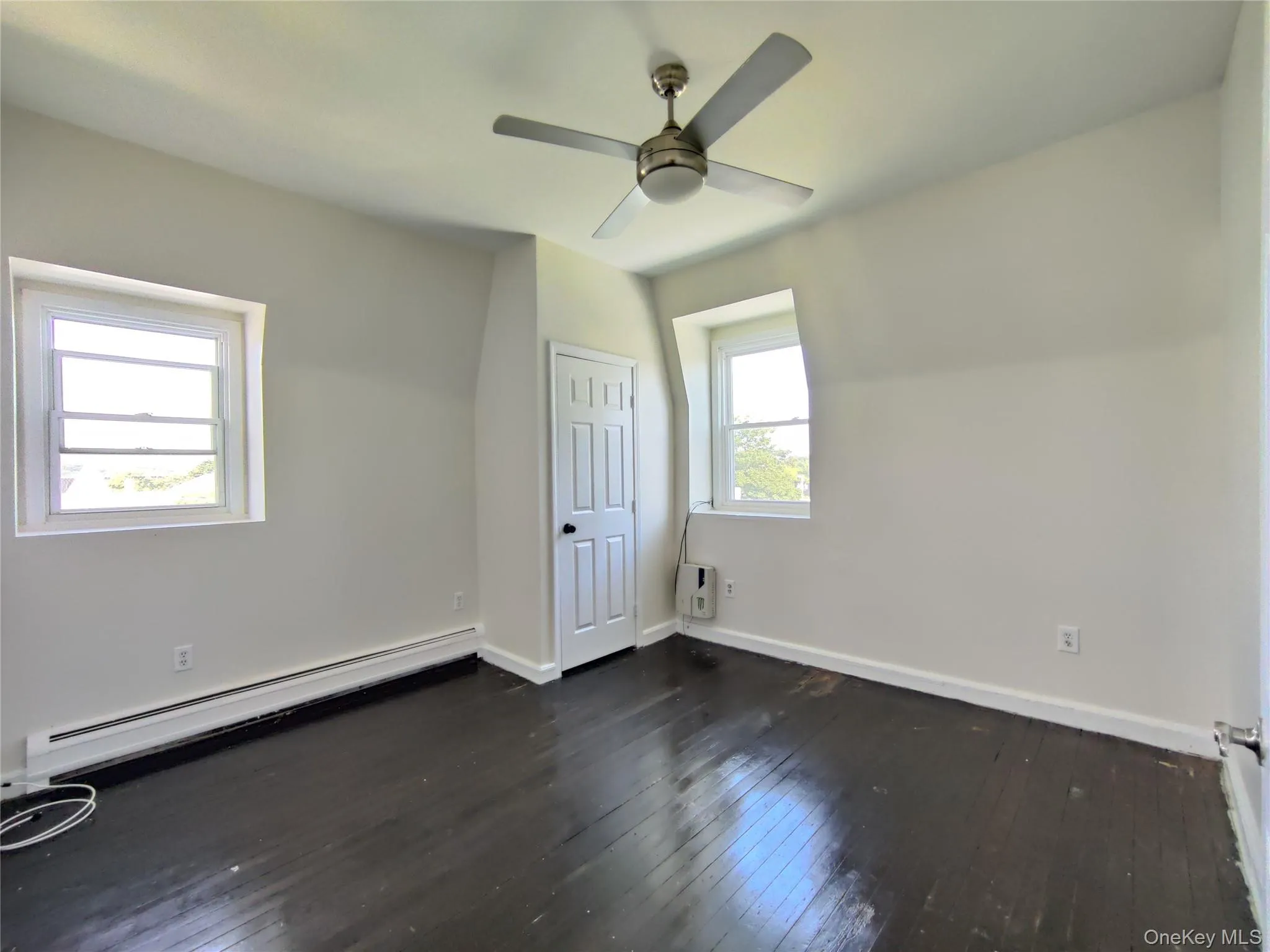 Unfurnished bedroom featuring a baseboard radiator, dark wood finished floors, and a ceiling fan Unfurnished bedroom featuring a baseboard radiator, dark wood finished floors, and a ceiling fan