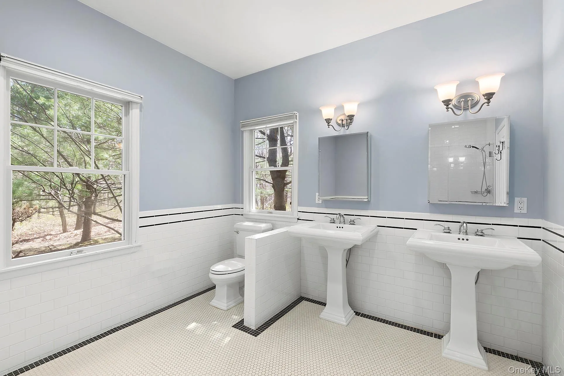 Bathroom with a wainscoted wall, tile walls, tile patterned floors, and a shower Bathroom with a wainscoted wall, tile walls, tile patterned floors, and a shower